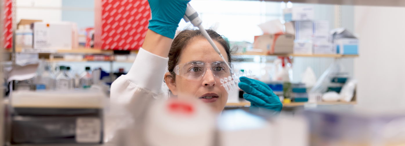 A female scientist in the lab pipetting liquid into a test tube.